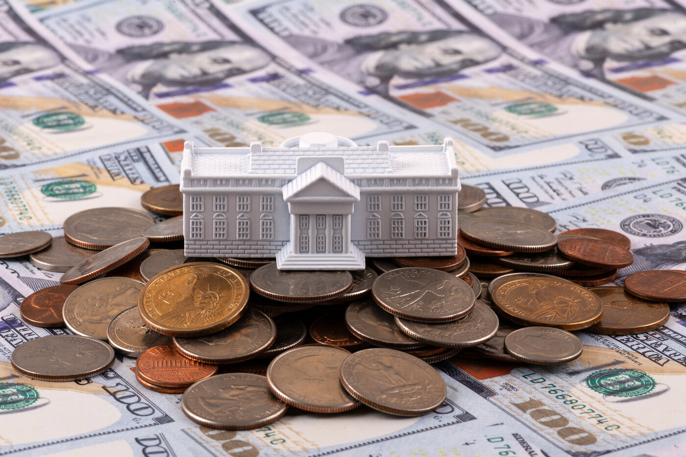 Miniature symbolic residence of the US President - White House on a stack of American coins and bills